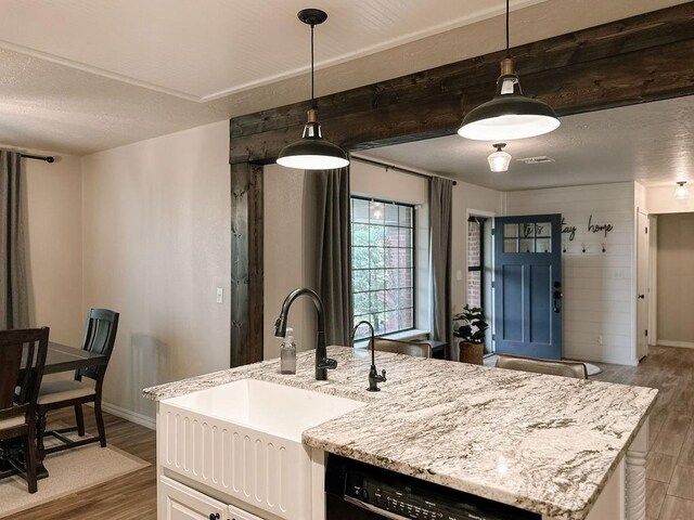 kitchen featuring wood finished floors, a sink, baseboards, black dishwasher, and white cabinetry