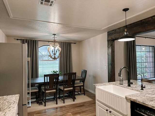 dining space featuring baseboards, a chandelier, wood finished floors, and visible vents
