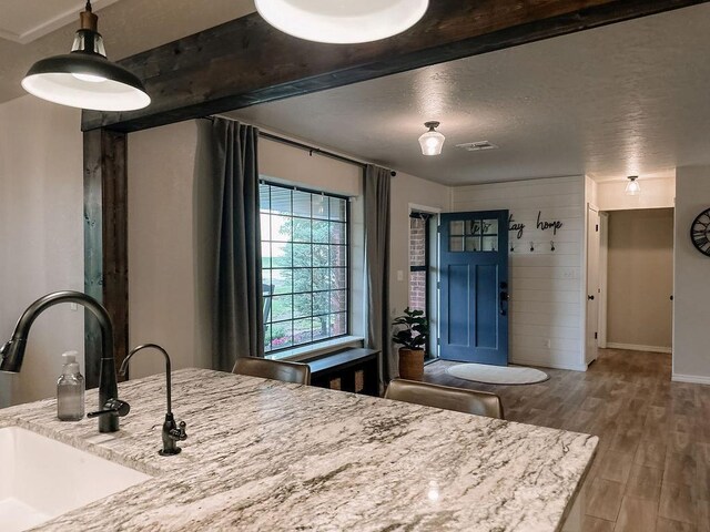 interior space featuring a textured ceiling, visible vents, wood finished floors, a sink, and baseboards