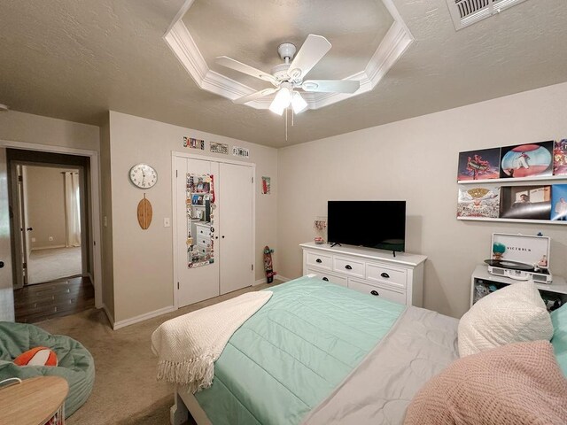 carpeted bedroom with a textured ceiling, a ceiling fan, baseboards, visible vents, and a closet