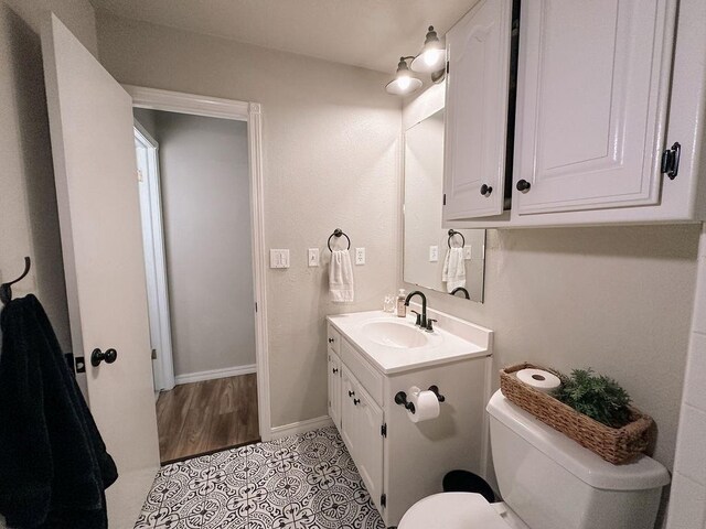 bathroom featuring vanity, baseboards, tile patterned flooring, and toilet