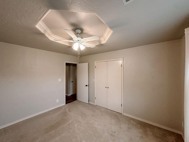 unfurnished bedroom with a textured ceiling, baseboards, light colored carpet, and ceiling fan