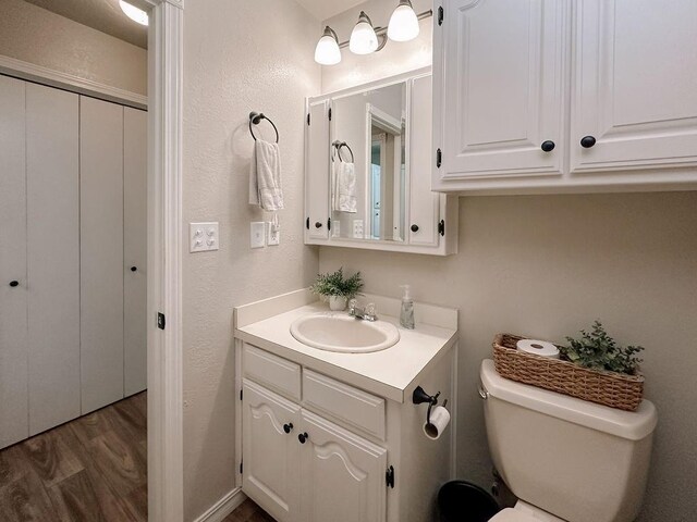 bathroom featuring vanity, a textured wall, wood finished floors, and toilet