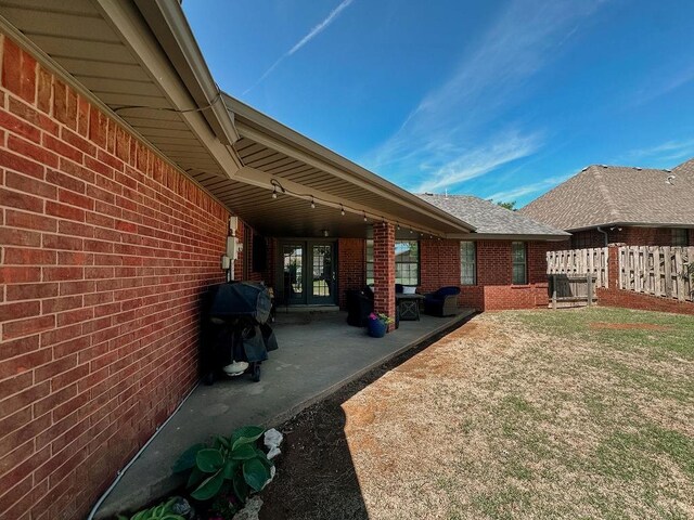 view of yard featuring a patio, fence, and french doors