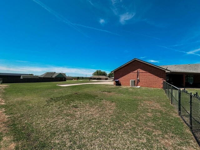 view of yard featuring central AC and fence