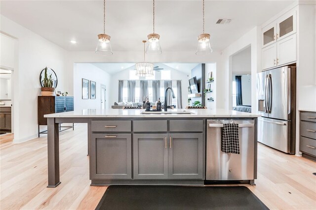 kitchen with a sink, light countertops, gray cabinets, stainless steel appliances, and light wood-type flooring