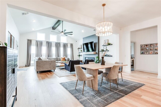 dining room featuring beamed ceiling, wood finished floors, ceiling fan with notable chandelier, and a fireplace