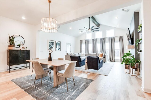 dining space with beam ceiling, high vaulted ceiling, ceiling fan with notable chandelier, light wood-type flooring, and visible vents