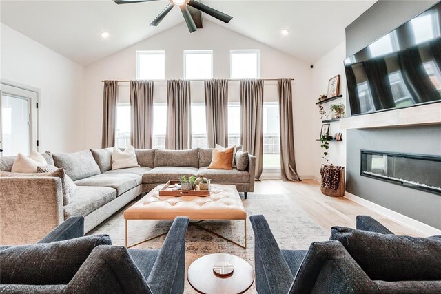 living room with a glass covered fireplace, wood finished floors, beamed ceiling, ceiling fan, and high vaulted ceiling