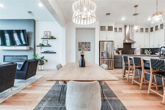 dining area featuring recessed lighting, visible vents, a glass covered fireplace, and light wood-type flooring