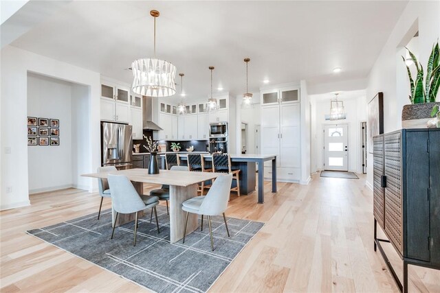dining area featuring light wood-style floors, baseboards, recessed lighting, and a chandelier