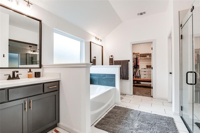 bathroom featuring visible vents, vaulted ceiling, a stall shower, vanity, and a spacious closet