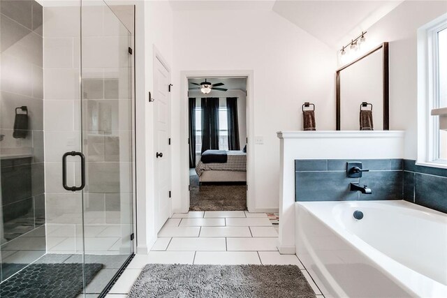 bathroom with a healthy amount of sunlight, tile patterned floors, vaulted ceiling, and a bath