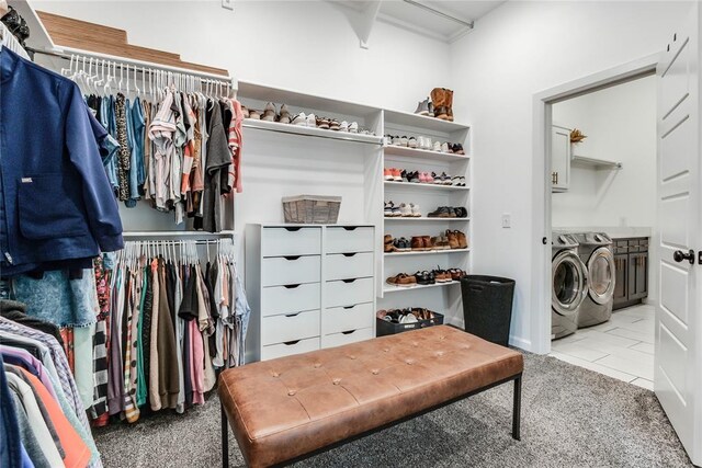 spacious closet featuring light colored carpet, light tile patterned floors, and washer and dryer