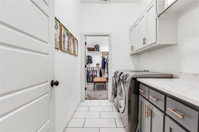 washroom featuring cabinet space, light tile patterned flooring, and washer and clothes dryer