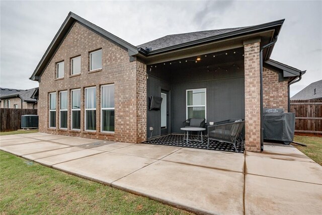 rear view of house with brick siding, a patio area, and central air condition unit