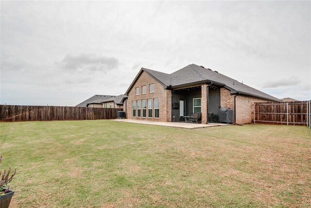 back of property featuring a fenced backyard, a yard, a patio area, and brick siding