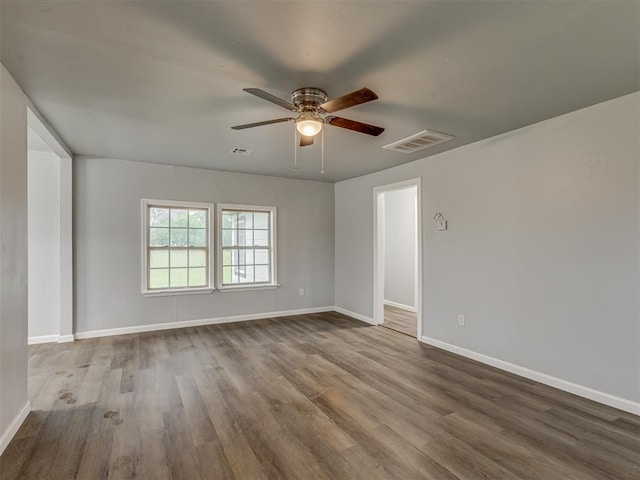 unfurnished room featuring baseboards, ceiling fan, wood finished floors, and visible vents
