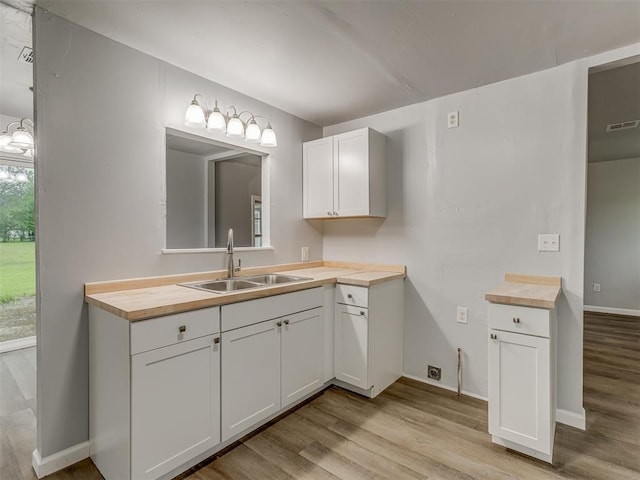 bathroom featuring baseboards, wood finished floors, visible vents, and vanity