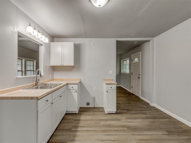 kitchen featuring a sink, light wood-style floors, wood counters, white cabinetry, and baseboards