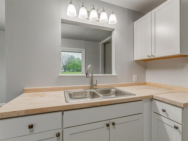kitchen featuring white cabinetry, wooden counters, and a sink