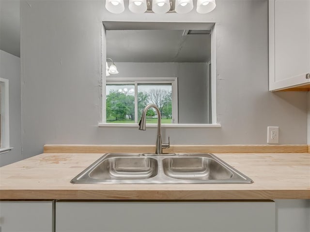 interior details featuring a sink, wood counters, and white cabinetry