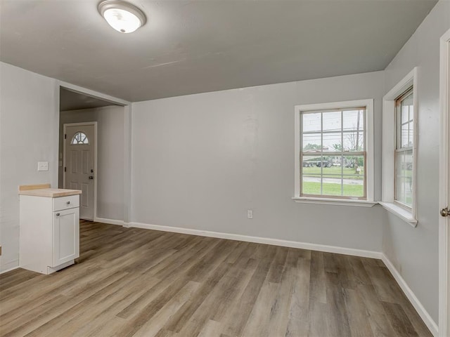 empty room with baseboards and light wood-type flooring