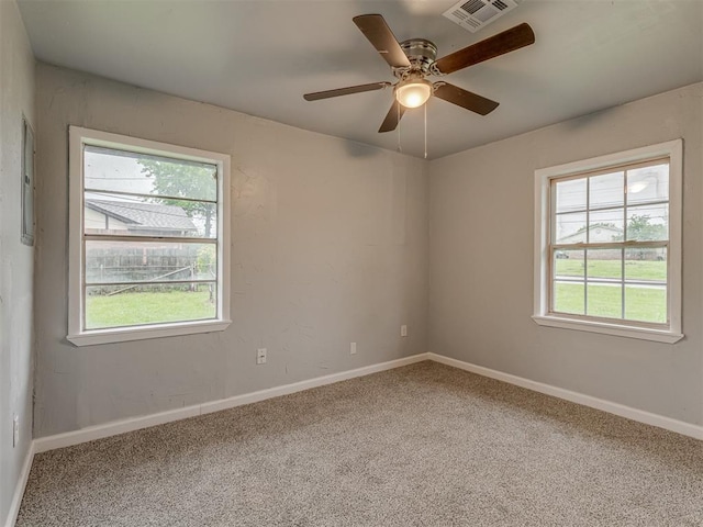 spare room with carpet floors, baseboards, a ceiling fan, and visible vents