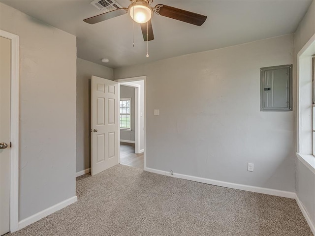 empty room with visible vents, baseboards, ceiling fan, electric panel, and carpet