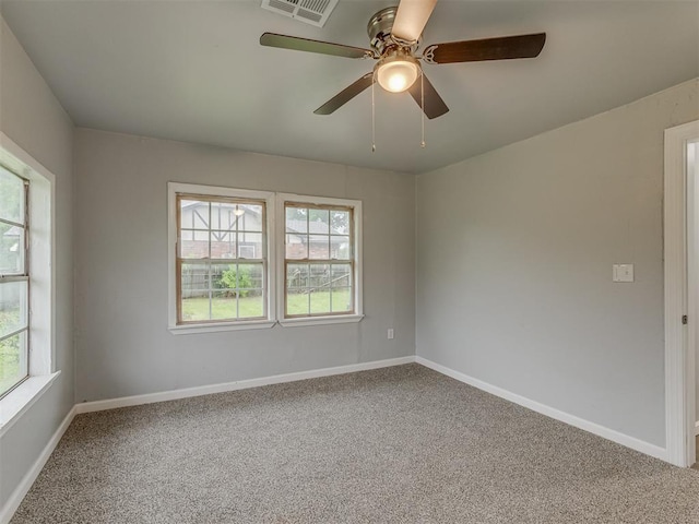 carpeted spare room featuring baseboards, a ceiling fan, and visible vents