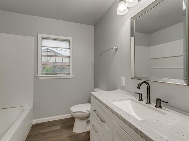 bathroom with vanity, baseboards, wood finished floors, and toilet