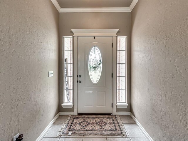 entryway with baseboards, ornamental molding, and a textured wall