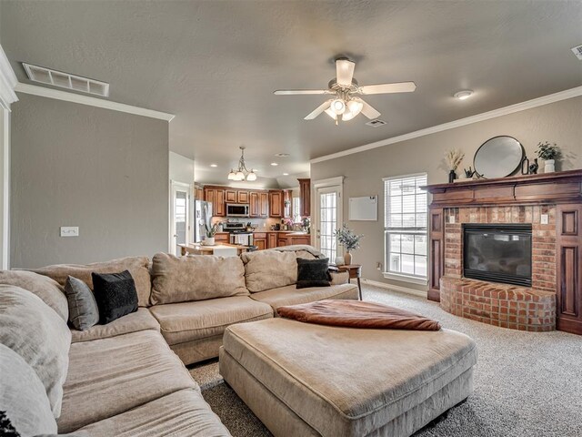 living area featuring ceiling fan, light colored carpet, a fireplace, visible vents, and ornamental molding