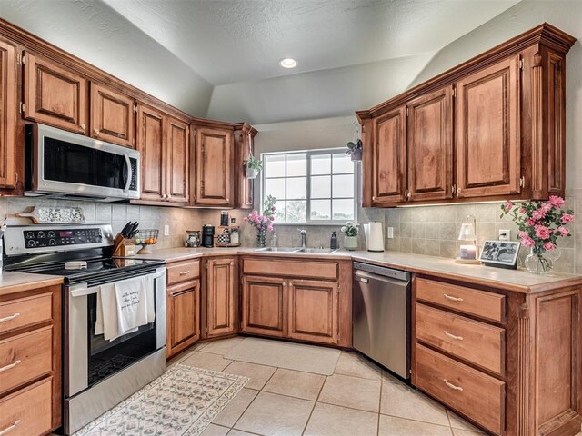 kitchen featuring light countertops, stainless steel appliances, a sink, and lofted ceiling