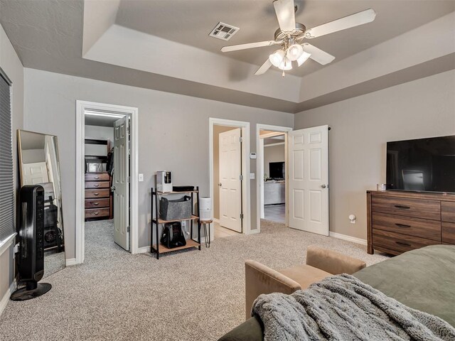 carpeted bedroom featuring a raised ceiling, a ceiling fan, baseboards, a spacious closet, and visible vents