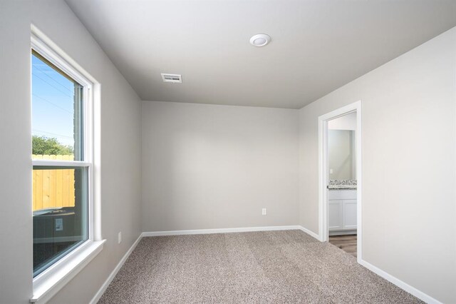 empty room featuring visible vents, carpet, and baseboards