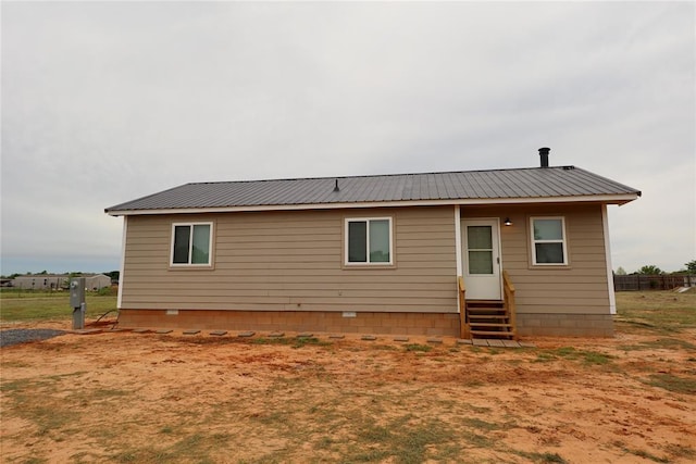 back of house with entry steps and metal roof