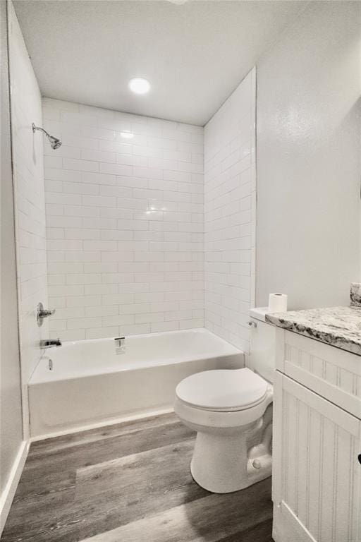 bathroom with wood finished floors, toilet, bathing tub / shower combination, and vanity