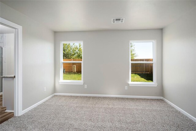 carpeted empty room with visible vents and baseboards