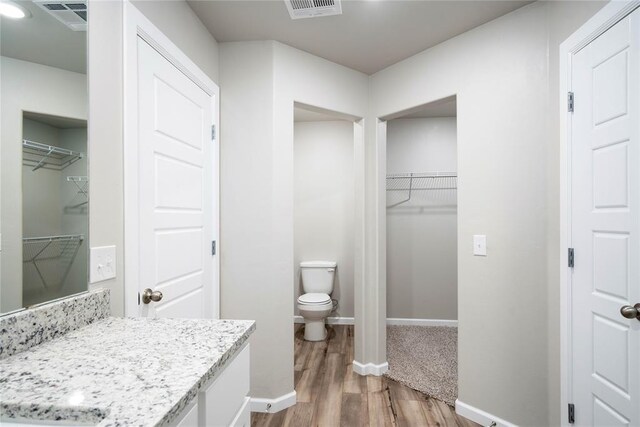 bathroom with vanity, toilet, wood finished floors, and visible vents
