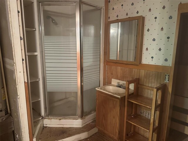bathroom featuring wallpapered walls, a shower stall, and vanity