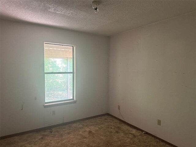 spare room with baseboards and a textured ceiling