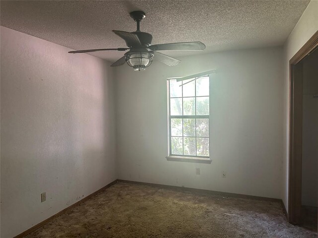 carpeted empty room featuring baseboards, a textured ceiling, and ceiling fan