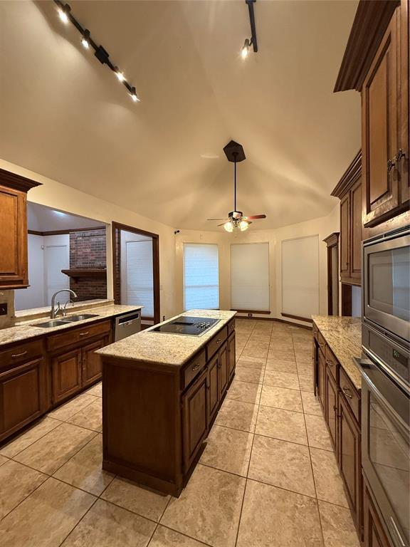 3900 Chickasha, Edmond, OK 73013 - kitchen featuring a kitchen island, a sink, track lighting, lofted ceiling, and stainless steel appliances