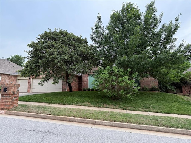 3900 Chickasha, Edmond, OK 73013 - obstructed view of property with brick siding, a front lawn, an attached garage, and driveway