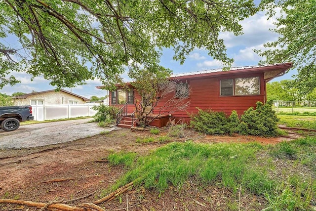 view of front of house featuring fence and metal roof