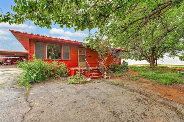 view of front of property featuring driveway, metal roof, and a carport