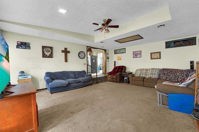 living area featuring visible vents, carpet, a textured ceiling, and a ceiling fan