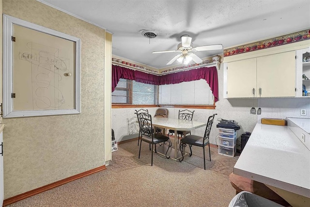dining area featuring ceiling fan, light carpet, a textured ceiling, baseboards, and visible vents
