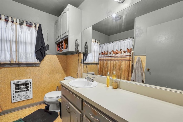 full bathroom with heating unit, vanity, and toilet
